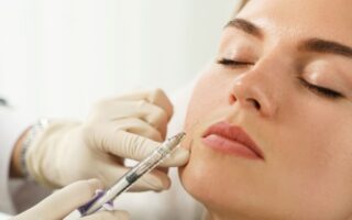 Profissional aplica injeção estética na face de paciente, em close, durante procedimento de harmonização facial com preenchimento dérmico.